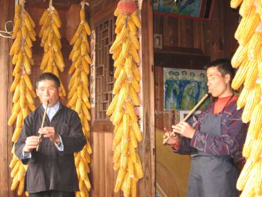 Two men playing reed flutes in Qingman Miao village 